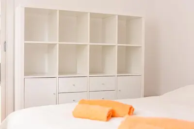 a white bedroom with white shelves and a bed at Apartment Lakeside Cerknica in Cerknica