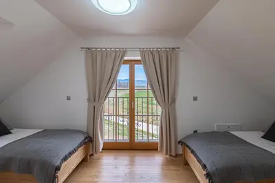 a bedroom with two beds and a large window at Domačija Vrški in Slovenska Bistrica