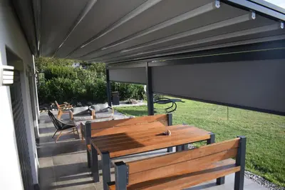 a covered patio with benches and a large screen at Domačija Vrški in Slovenska Bistrica