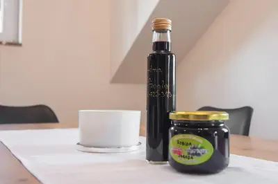 a bottle and a jar on a table with a candle at Apartma Tia in Zreče