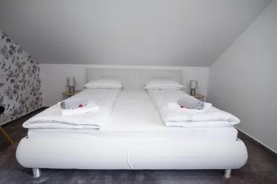 a bedroom with two beds with white sheets and towels at Apartma Tia in Zreče