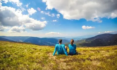 a couple sitting on top of a grassy hill at APARTMA NIKA in Ribnica na Pohorju