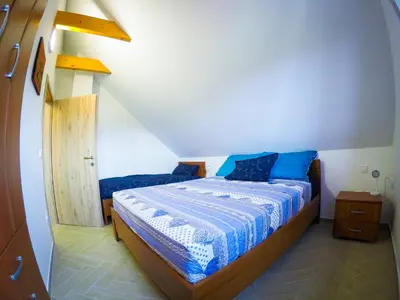 a bedroom with a bed with blue pillows on it at APARTMA NIKA in Ribnica na Pohorju