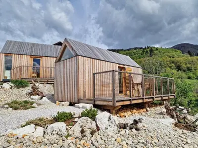 a wooden house with a deck on the rocks at GoLife Center Glamping in Laze v Tuhinju