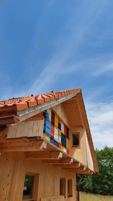 a wooden house with a rainbow colored roof at Grajska kmetija in Kočevje