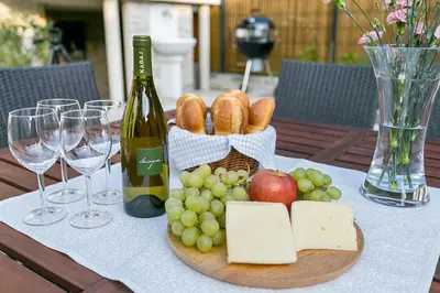 a table with a plate of cheese and grapes and a bottle of wine at Angel Boutique Home - Entire premium house in Laško