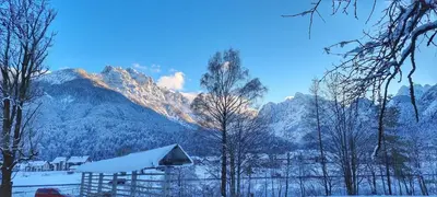 a snow covered mountain in the distance with a house at Apartma Uršič in Kranjska Gora