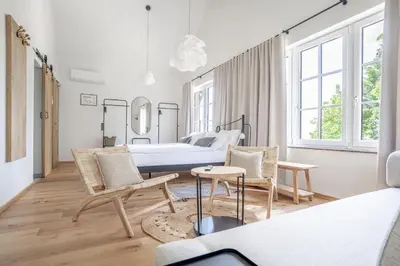 a bedroom with a bed and two chairs and a table at SIBON Wine & Spa Resort Jeruzalem in Ljutomer
