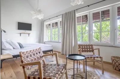 a bedroom with a bed and chairs and windows at SIBON Wine & Spa Resort Jeruzalem in Ljutomer