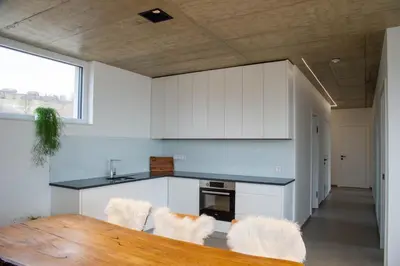a kitchen with white cabinets and a wooden table at VOO residence in Malečnik