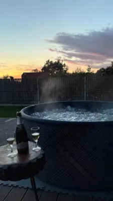 a hot tub with two glasses of wine on a table at VOO residence in Malečnik