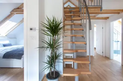 a spiral staircase in a bedroom with a bed and plants at Bright & Spacious Loft In The Heart Of Old Town in Ljubljana