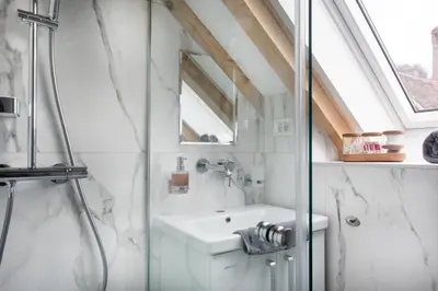a bathroom with a glass shower and a sink at Bright & Spacious Loft In The Heart Of Old Town in Ljubljana