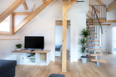a living room with a tv and a staircase at Bright & Spacious Loft In The Heart Of Old Town in Ljubljana