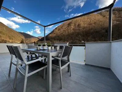 a table and chairs on a balcony with a view at HOLIDAY HOUSE - River Bača in Most na Soči