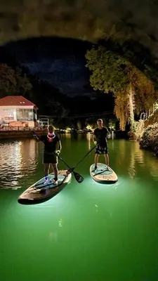 two men are standing on paddle boards in the water at HOLIDAY HOUSE - River Bača in Most na Soči