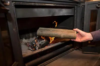 a person holding a pot over a fire in an oven at Cottage Suha in Bohinj