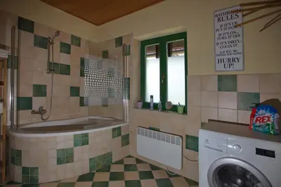 a bathroom with a tub and a sink and a washing machine at Cottage Suha in Bohinj