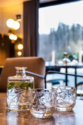 a glass jar and two glasses on a table at Hotel Čad in Ljubljana