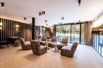 a waiting room with chairs and tables and windows at Hotel Čad in Ljubljana