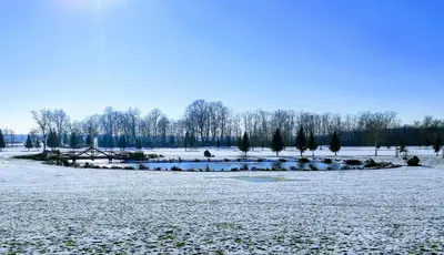 a field covered in snow with trees and a bridge at Apartma MAX in Moravske Toplice