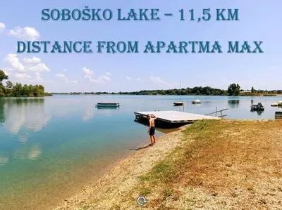 a woman standing on the shore of a lake with a boat at Apartma MAX in Moravske Toplice