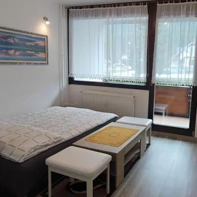 a bedroom with a bed and two chairs and a window at Apartma Kuhar in Kranjska Gora