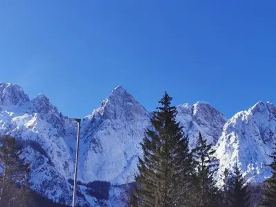 a snow covered mountain with a pole in the foreground at Apartma Kuhar in Kranjska Gora