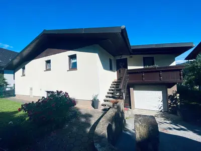 a large white house with a staircase and a garage at Apartma KAMNITNK in Škofja Loka