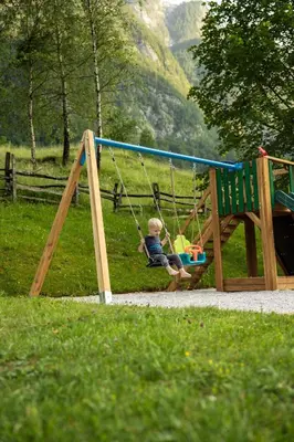 a young boy sitting on a swing in a park at Organic Tourist Farm Pri Plajerju in Trenta
