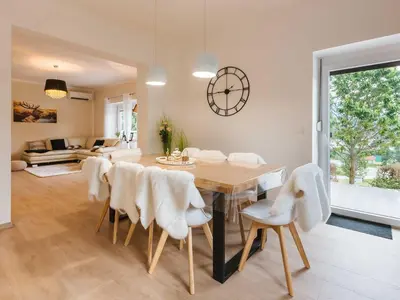 a dining room with a table and white chairs at Villa M&J Bled in Zgornje Gorje