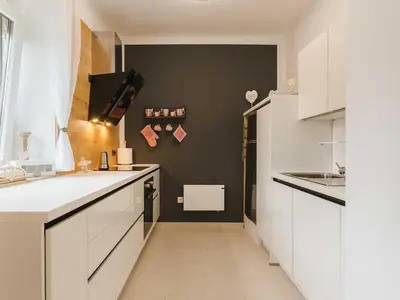 a kitchen with white cabinets and a black wall at Villa M&J Bled in Zgornje Gorje