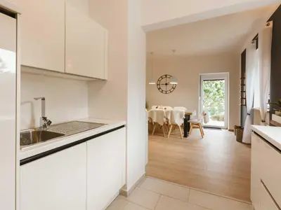 a kitchen with white cabinets and a dining room at Villa M&J Bled in Zgornje Gorje