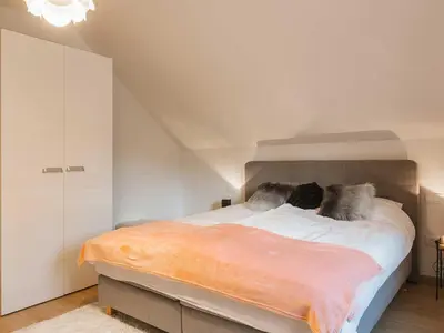 a bedroom with a large bed with an orange blanket at Villa M&J Bled in Zgornje Gorje