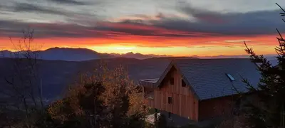 a sunset with a house and mountains in the background at Studio 1111 with Sauna & Hot Tub in Dravograd