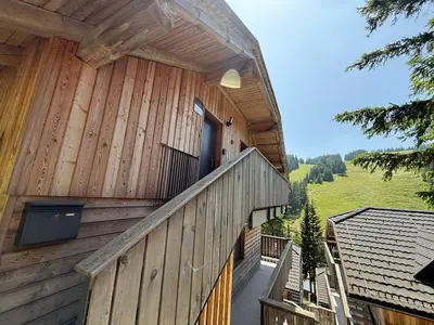 a wooden building with a balcony with a door at OTTA Apartments Golte C2 in Mozirska Koča