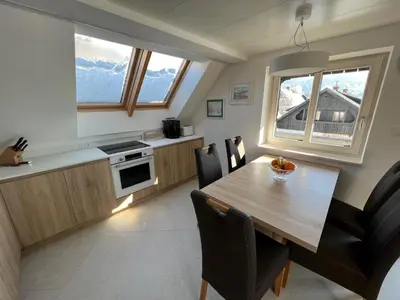 a kitchen and dining room with a wooden table and chairs at Gloria Holiday - Apartment Bohinj in Bohinj