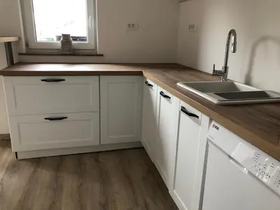 a kitchen with white cabinets and a sink and a window at Garden House in Kranj