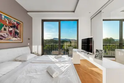 a white bedroom with a white bed and a tv at Contemporary apartment with rooftop terrace in Maribor in Maribor