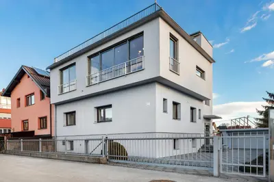 a white house with a fence in front of it at Contemporary apartment with rooftop terrace in Maribor in Maribor