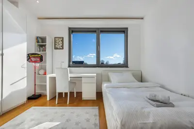 a bedroom with two beds and a desk and a window at Contemporary apartment with rooftop terrace in Maribor in Maribor