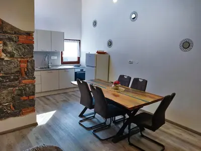 a dining room with a wooden table and chairs at Homestead Zavadlal - Domačija Zavadlal in Komen