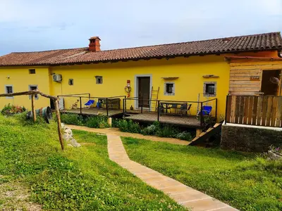 a yellow house with a pathway in front of it at Homestead Zavadlal - Domačija Zavadlal in Komen