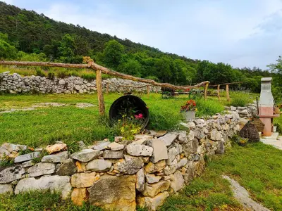 a stone wall with a wheel in a yard at Homestead Zavadlal - Domačija Zavadlal in Komen