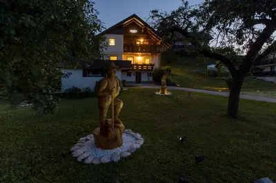 a statue of a man sitting on a stump in front of a house at Alpinia apartments in Bled