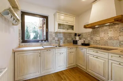 a kitchen with white cabinets and a window and a sink at Alpinia apartments in Bled
