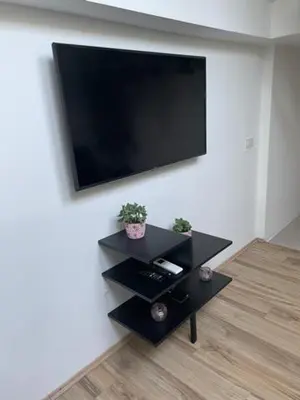 a flat screen tv hanging on a wall with a table at Cute Spot in Ljubljana in Ljubljana