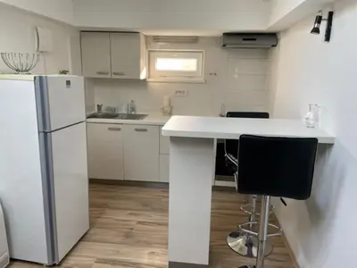 a kitchen with a refrigerator and a counter with two chairs at Cute Spot in Ljubljana in Ljubljana