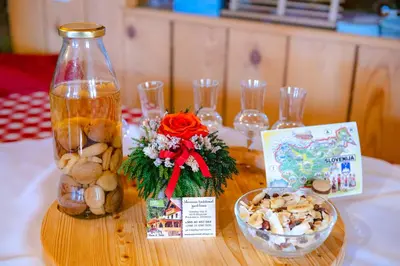 a wooden table with a bottle and a bowl of mushrooms at Farm Stay Trlej in Begunje na Gorenjskem