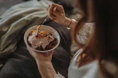 a woman eating a bowl of food with a fork at Glamping Senesalina in Kojsko